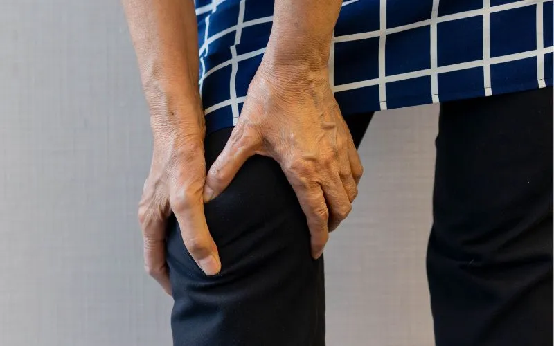 Close-up of hands holding a knee, showcasing joint care tips to prevent bone aches during colder weather